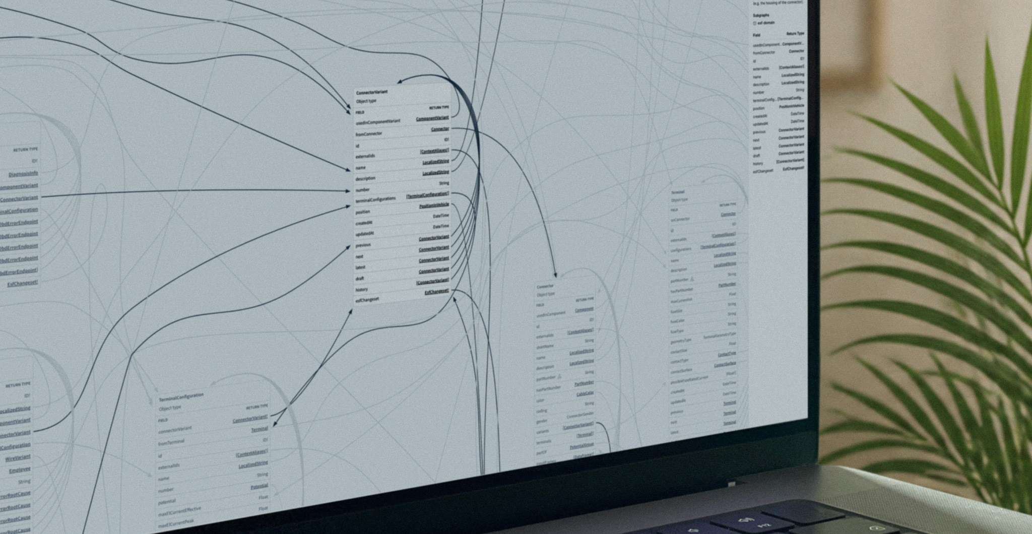 A laptop screen showing an engineering knowledge graph: component and variant schema tables connected by curved relationship edges